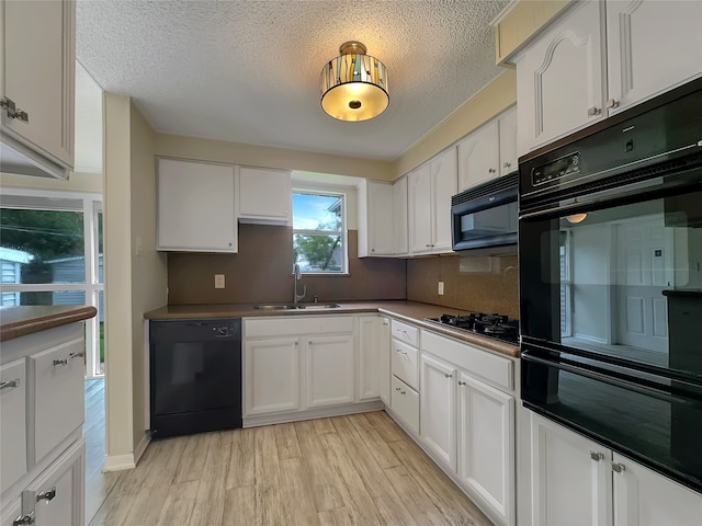 kitchen with white cabinetry, light wood-type flooring, a textured ceiling, black appliances, and sink