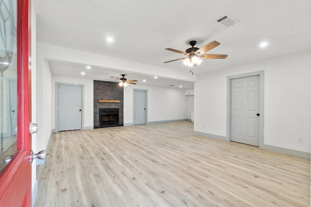 unfurnished living room with a stone fireplace, light hardwood / wood-style floors, and ceiling fan