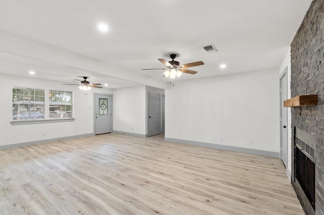 unfurnished living room featuring ceiling fan, a fireplace, and light hardwood / wood-style floors