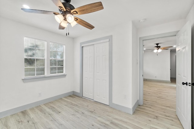 unfurnished bedroom featuring light hardwood / wood-style flooring, ceiling fan, and a closet