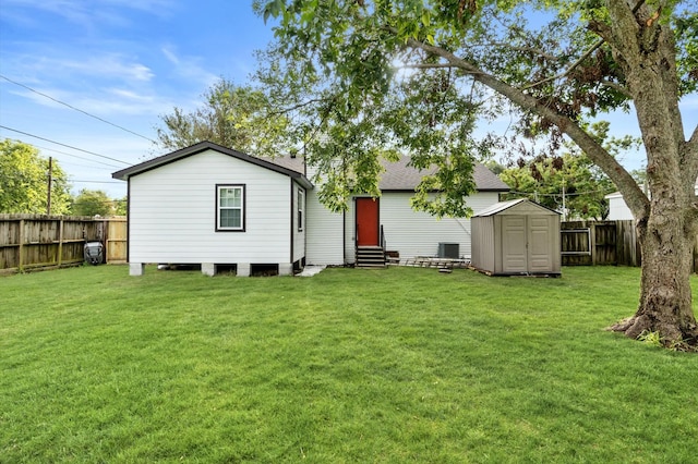 rear view of house featuring a shed, a lawn, and central air condition unit