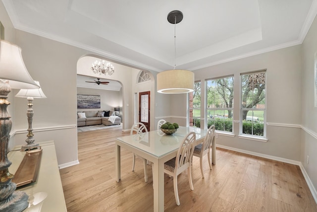 dining room with crown molding, a raised ceiling, and light wood-type flooring