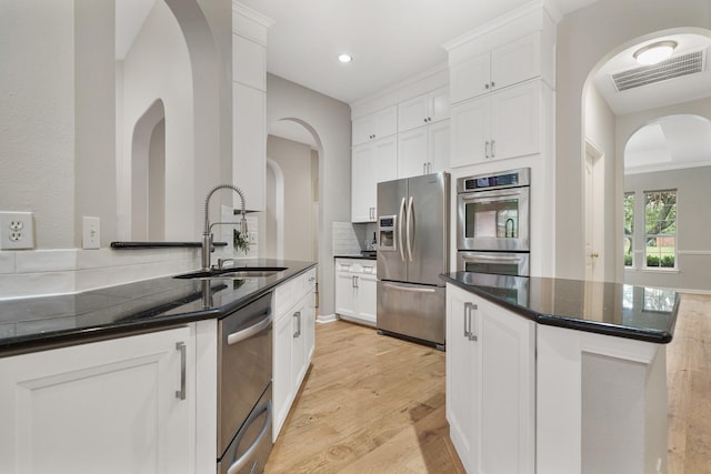 kitchen with white cabinetry, sink, stainless steel appliances, and dark stone countertops