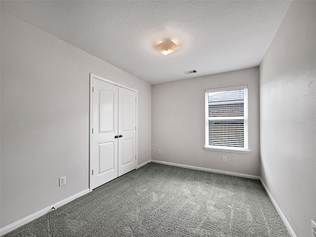 unfurnished bedroom with a textured ceiling, a closet, and carpet flooring