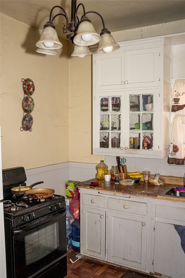 kitchen featuring sink, dark parquet flooring, black range with gas cooktop, and white cabinets