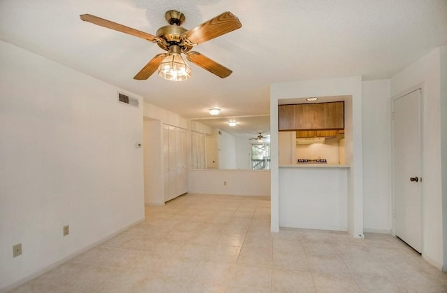 unfurnished room with light tile patterned flooring, a ceiling fan, visible vents, and baseboards