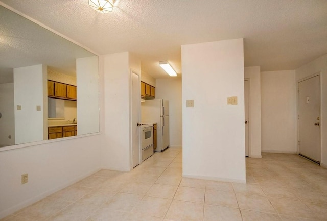 interior space with light tile patterned floors, white appliances, a textured ceiling, and brown cabinets