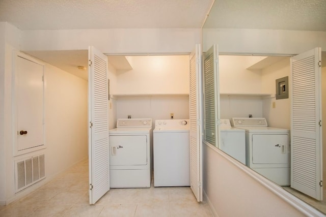 laundry room featuring washing machine and dryer, light tile patterned floors, and a textured ceiling