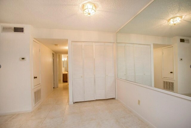 unfurnished bedroom featuring multiple closets, a textured ceiling, and light tile patterned floors