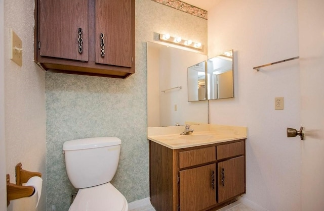 half bath featuring baseboards, toilet, and vanity