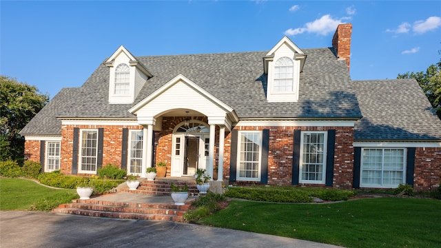 cape cod home featuring a front lawn