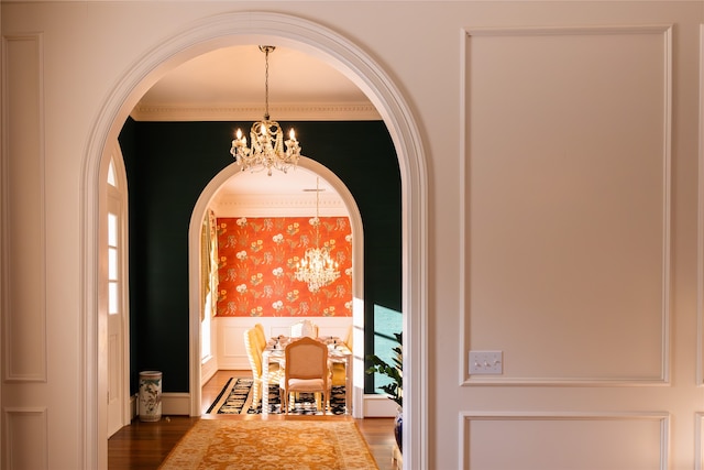 interior space featuring ornamental molding, wood-type flooring, and a chandelier