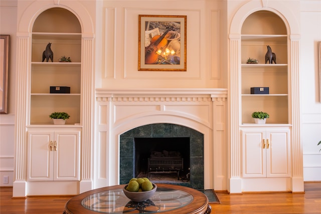 details with hardwood / wood-style flooring, built in shelves, and a high end fireplace