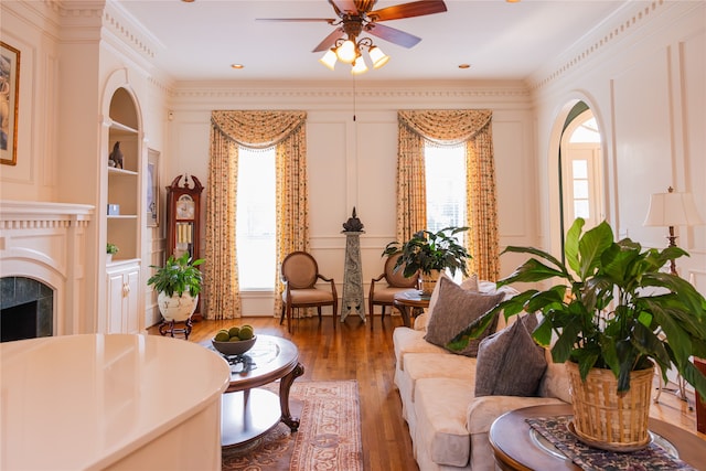 living room featuring hardwood / wood-style floors, crown molding, ceiling fan, and a wealth of natural light