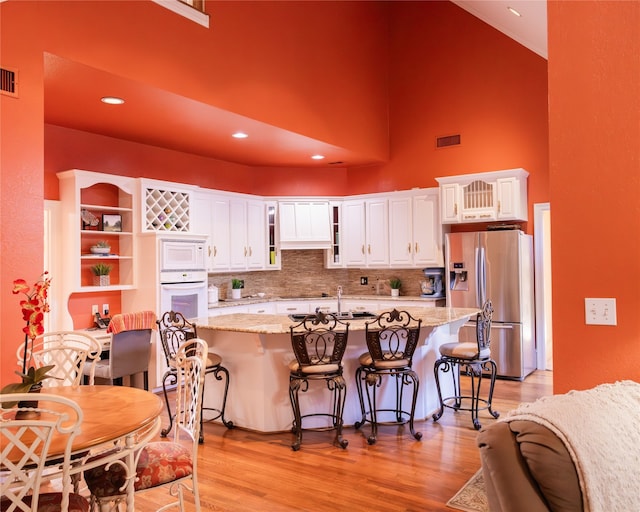 kitchen featuring white cabinetry, white appliances, and light hardwood / wood-style floors