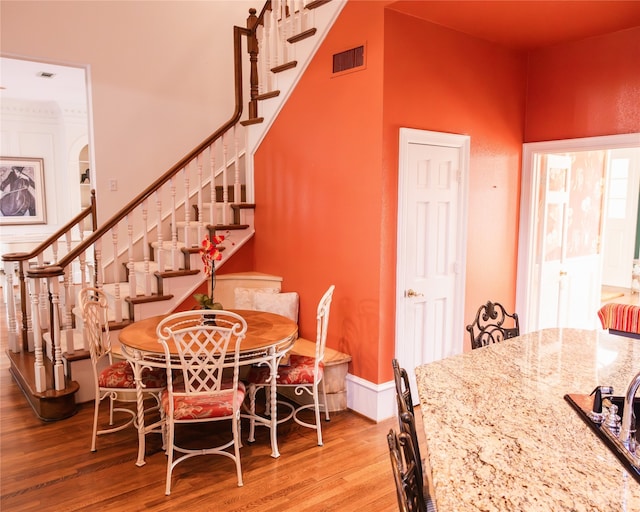 dining room with a high ceiling and light hardwood / wood-style flooring