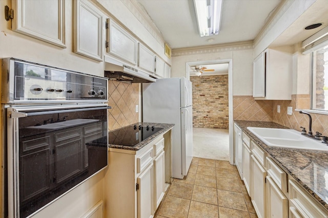 kitchen with sink, dark stone countertops, stainless steel oven, light carpet, and black electric cooktop