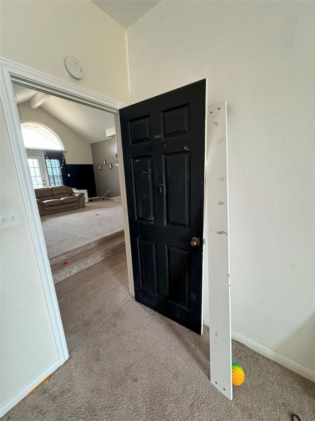 carpeted foyer featuring vaulted ceiling