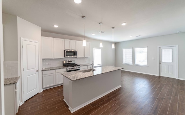 kitchen featuring an island with sink, decorative light fixtures, appliances with stainless steel finishes, and white cabinetry