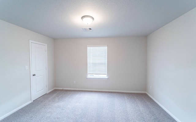 carpeted empty room with a textured ceiling