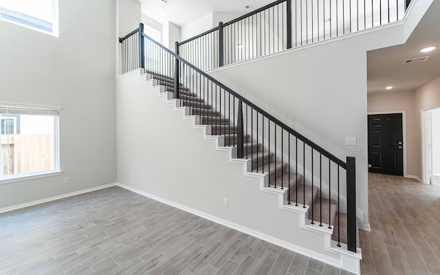 stairs with wood-type flooring, a high ceiling, and a wealth of natural light