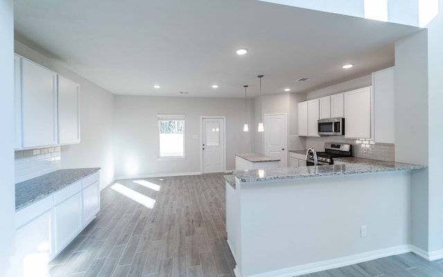 kitchen featuring kitchen peninsula, light hardwood / wood-style floors, stainless steel appliances, and white cabinets