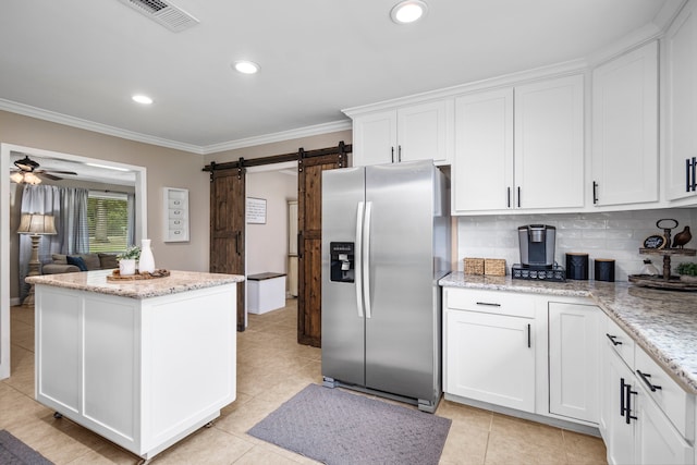 kitchen with ceiling fan, white cabinets, a barn door, and stainless steel fridge with ice dispenser