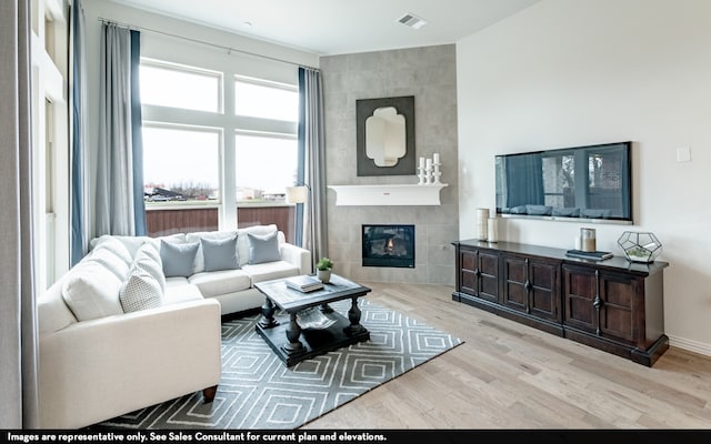 living room with tile walls, a tiled fireplace, and light hardwood / wood-style flooring