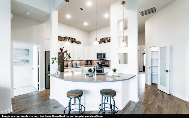 kitchen with dark hardwood / wood-style flooring, decorative backsplash, stainless steel appliances, and a high ceiling