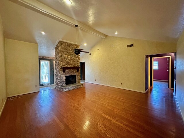 unfurnished living room featuring a stone fireplace, hardwood / wood-style flooring, and vaulted ceiling with beams