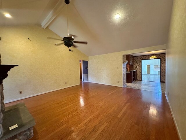 unfurnished living room with high vaulted ceiling, wood-type flooring, beam ceiling, and ceiling fan