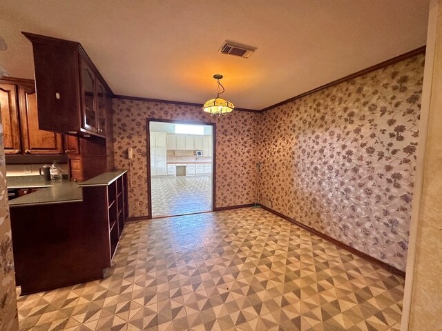 kitchen with hanging light fixtures, light tile patterned floors, and crown molding