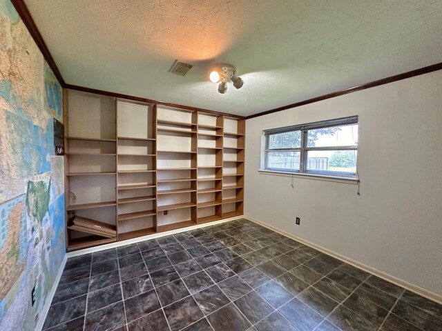 empty room with ornamental molding, dark tile patterned floors, and a textured ceiling