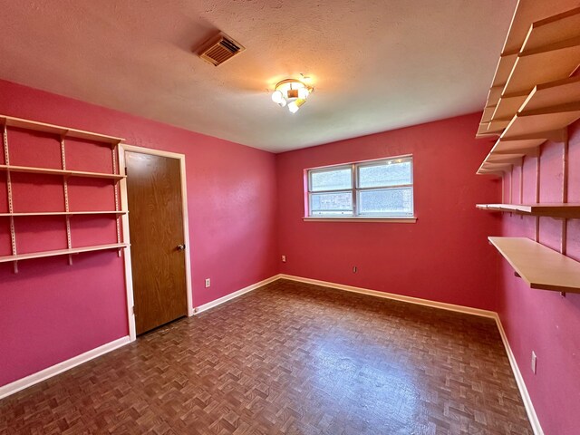 unfurnished bedroom featuring a textured ceiling and dark parquet flooring