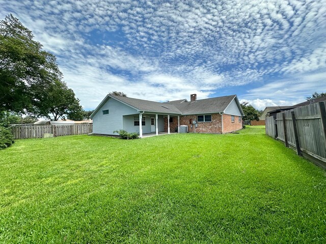 back of house featuring central AC, a lawn, and a patio area