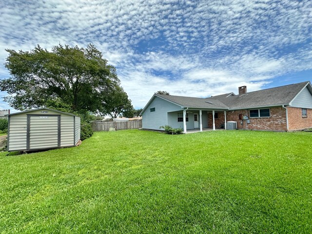 view of yard with central AC, a patio, and a shed