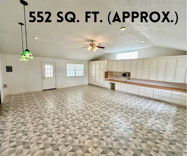 unfurnished living room featuring ceiling fan, light tile patterned floors, and vaulted ceiling