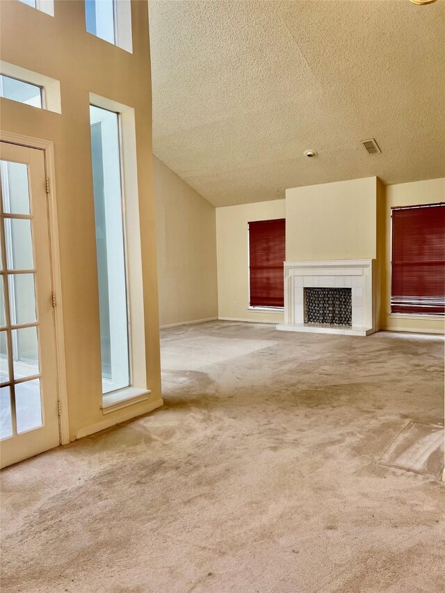 unfurnished living room featuring carpet, a textured ceiling, a fireplace, and visible vents