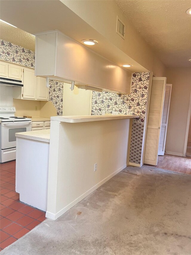 kitchen with white electric range oven, a peninsula, light countertops, under cabinet range hood, and dark carpet