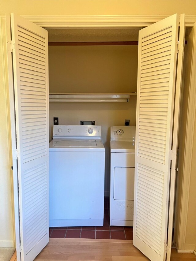 clothes washing area with washing machine and dryer, laundry area, and wood finished floors