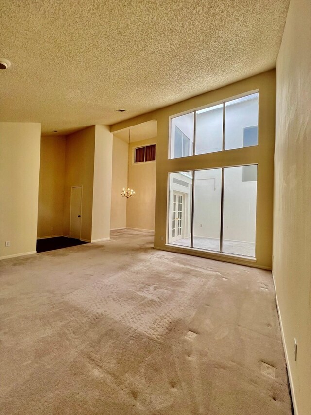 empty room featuring a textured ceiling, carpet flooring, and baseboards