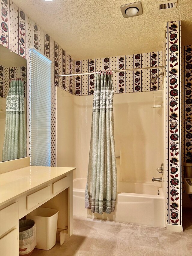 full bathroom featuring wallpapered walls, shower / bath combo with shower curtain, a textured ceiling, and vanity