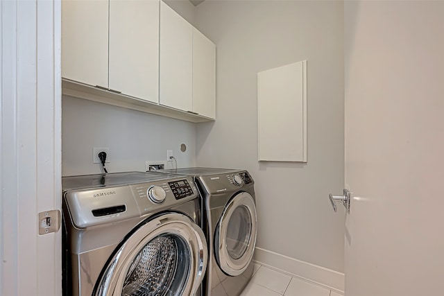 washroom featuring light tile patterned flooring, washing machine and clothes dryer, and cabinets