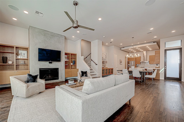 living room featuring a fireplace, hardwood / wood-style flooring, and ceiling fan with notable chandelier