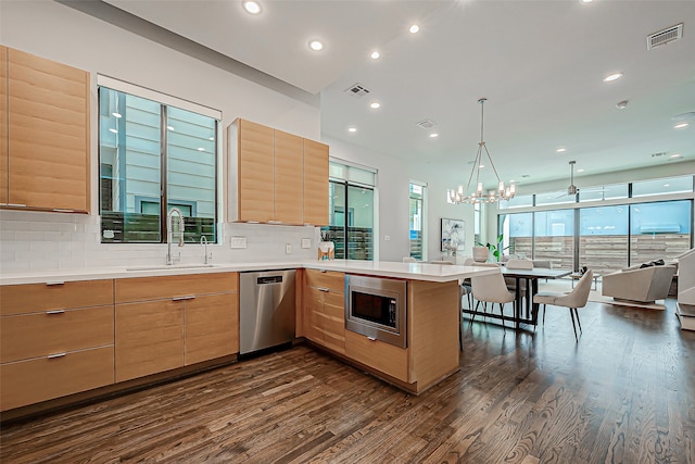 kitchen featuring sink, backsplash, kitchen peninsula, stainless steel appliances, and dark hardwood / wood-style floors