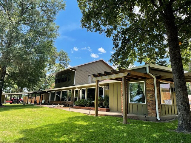 back of property featuring a pergola, a carport, and a lawn