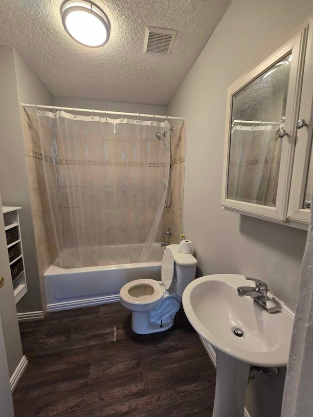 full bathroom with shower / tub combo, toilet, hardwood / wood-style floors, and a textured ceiling