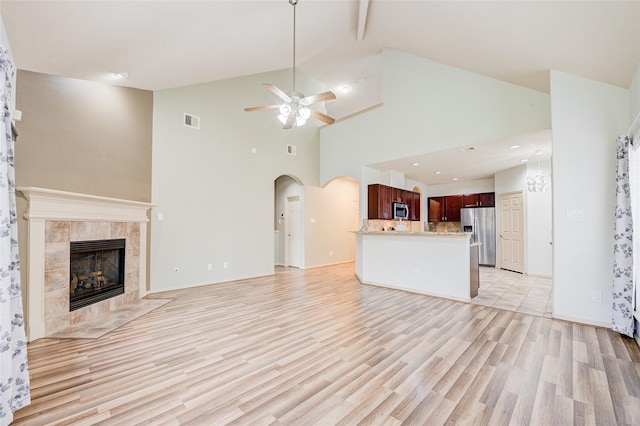 unfurnished living room featuring ceiling fan, a fireplace, high vaulted ceiling, and light hardwood / wood-style flooring