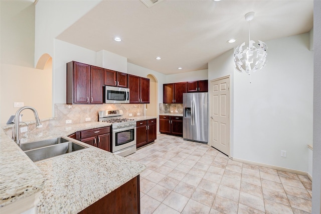 kitchen featuring pendant lighting, sink, backsplash, stainless steel appliances, and kitchen peninsula