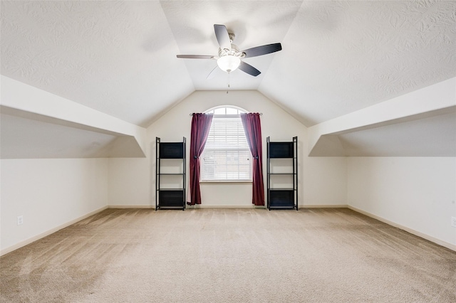 bonus room with ceiling fan, vaulted ceiling, light colored carpet, and a textured ceiling